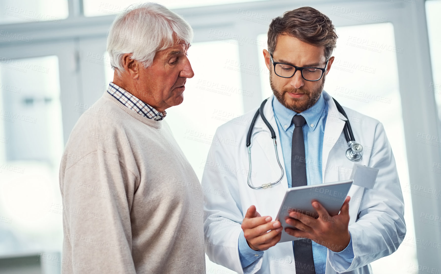 Buy stock photo Shot of a doctor discussing something on a digital tablet with a senior patient in a clinic