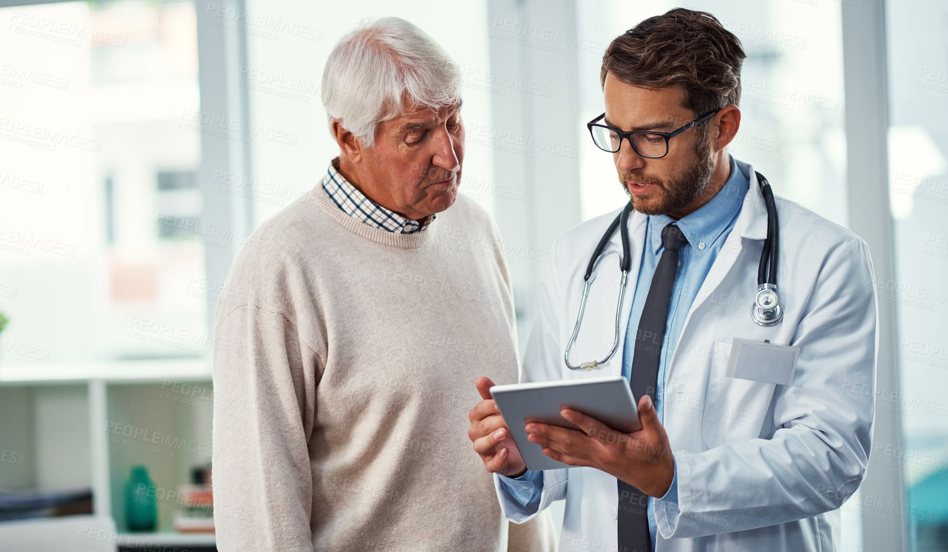 Buy stock photo Shot of a doctor discussing something on a digital tablet with a senior patient in a clinic