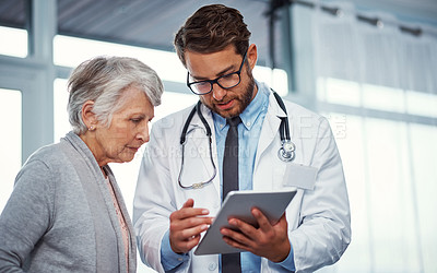 Buy stock photo Shot of a doctor discussing something on a digital tablet with a senior patient in a clinic