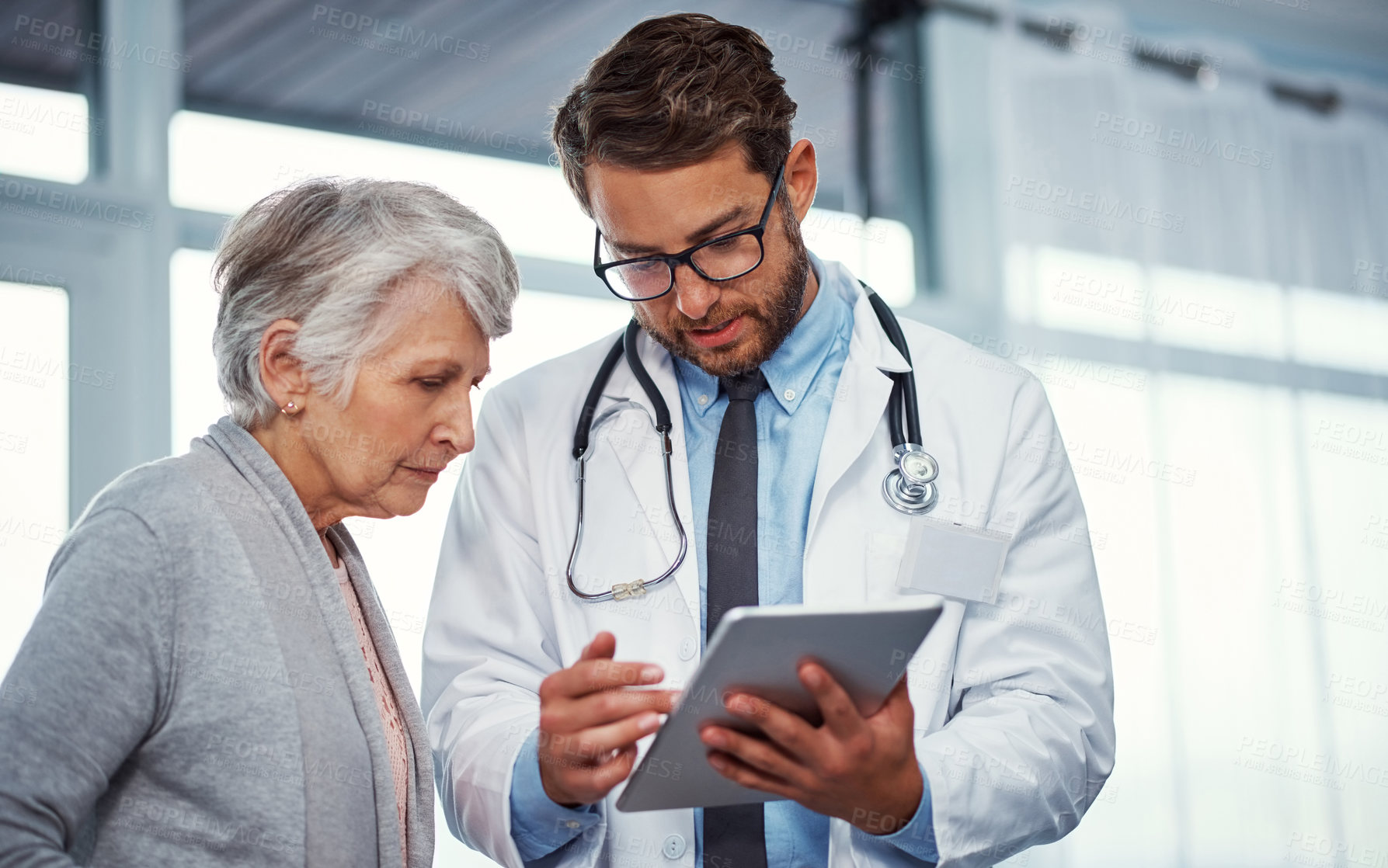 Buy stock photo Shot of a doctor discussing something on a digital tablet with a senior patient in a clinic