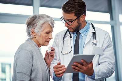 Buy stock photo Shot of a doctor discussing something on a digital tablet with a senior patient in a clinic