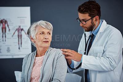 Buy stock photo Shot of a doctor examining a senior patient with a stethoscope in a clinic