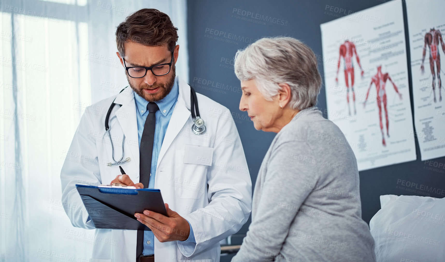 Buy stock photo Shot of a doctor writing notes while examining a senior patient in a clinic