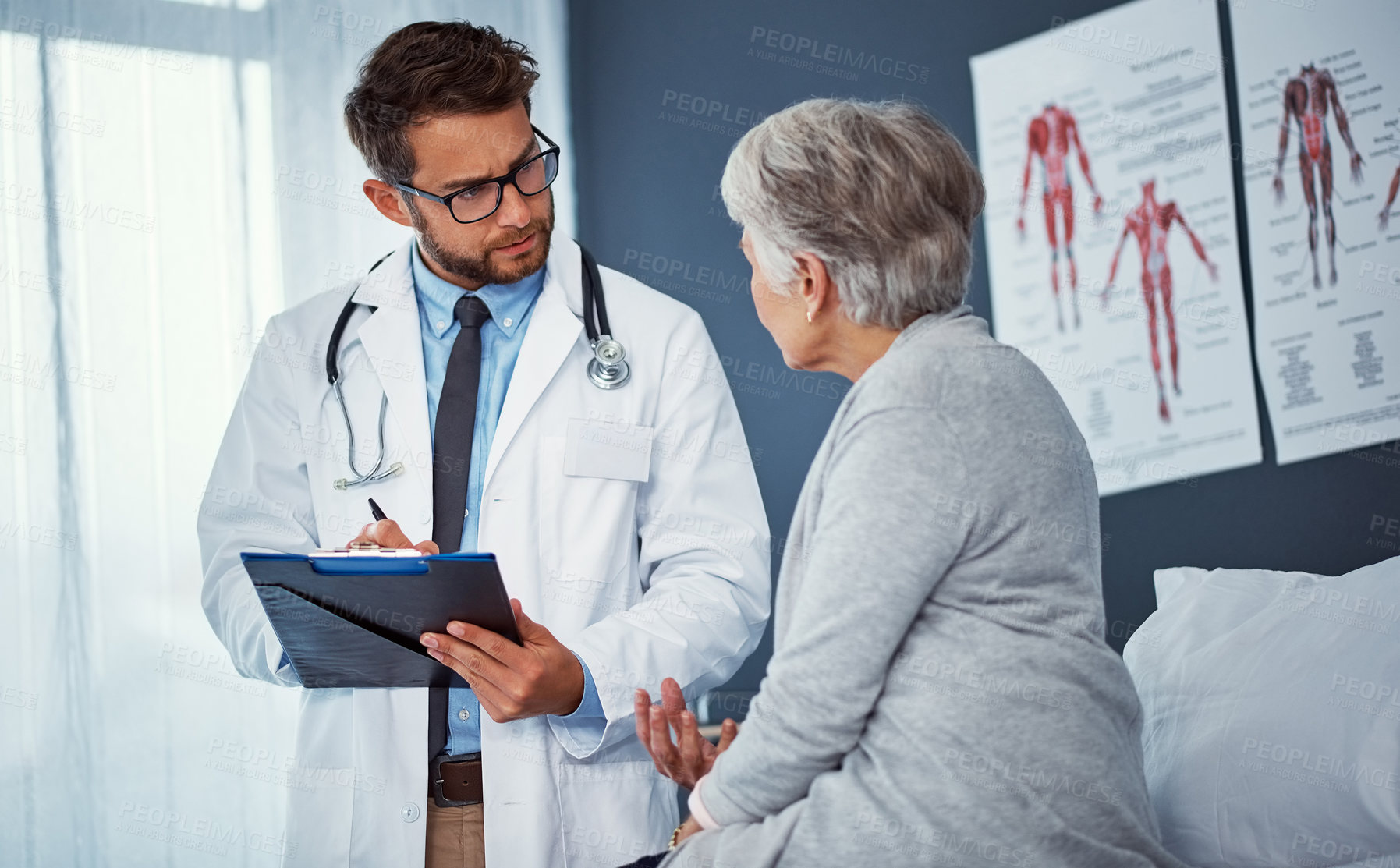 Buy stock photo Shot of a doctor writing notes while examining a senior patient in a clinic