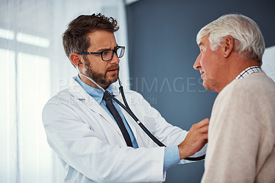 Buy stock photo Shot of a doctor examining a senior patient with a stethoscope in a clinic
