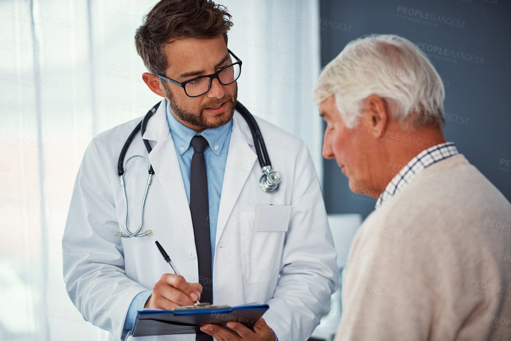 Buy stock photo Shot of a doctor writing notes while examining a senior patient in a clinic