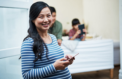 Buy stock photo Portrait of a pregnant woman using a digital tablet with her family in the background