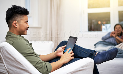Buy stock photo Shot of a man using a digital tablet with his family in the background