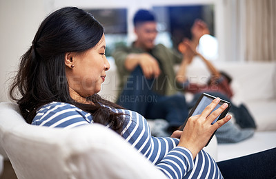 Buy stock photo Shot of a pregnant woman using a digital tablet with her family in the background