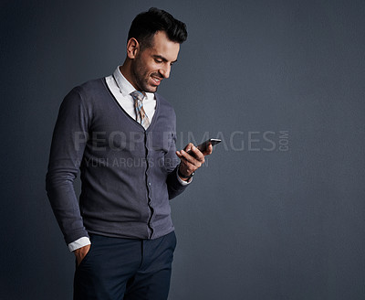 Buy stock photo Studio shot of a stylish young businessman using a mobile phone against a gray background