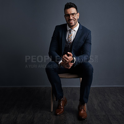 Buy stock photo Studio shot of a stylish young businessman sitting on a chair against a gray background