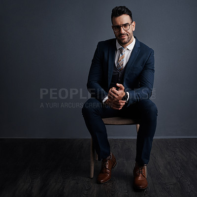 Buy stock photo Studio shot of a stylish young businessman sitting on a chair against a gray background