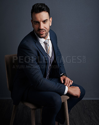 Buy stock photo Studio shot of a stylish young businessman sitting on a chair against a gray background