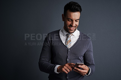 Buy stock photo Studio shot of a stylish young businessman using a mobile phone against a gray background