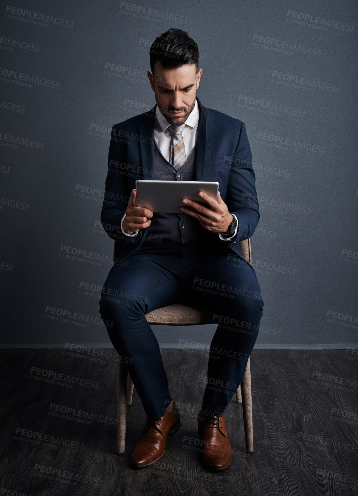 Buy stock photo Studio shot of a stylish young businessman using a digital tablet against a gray background