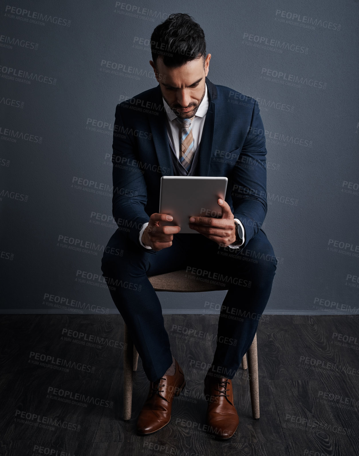 Buy stock photo Studio shot of a stylish young businessman using a digital tablet against a gray background