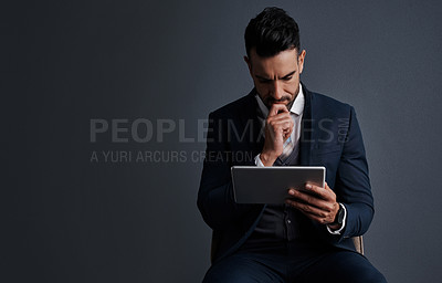 Buy stock photo Studio shot of a stylish young businessman using a digital tablet against a gray background
