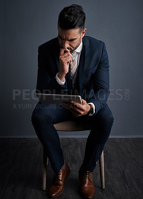 Buy stock photo Studio shot of a stylish young businessman using a digital tablet against a gray background