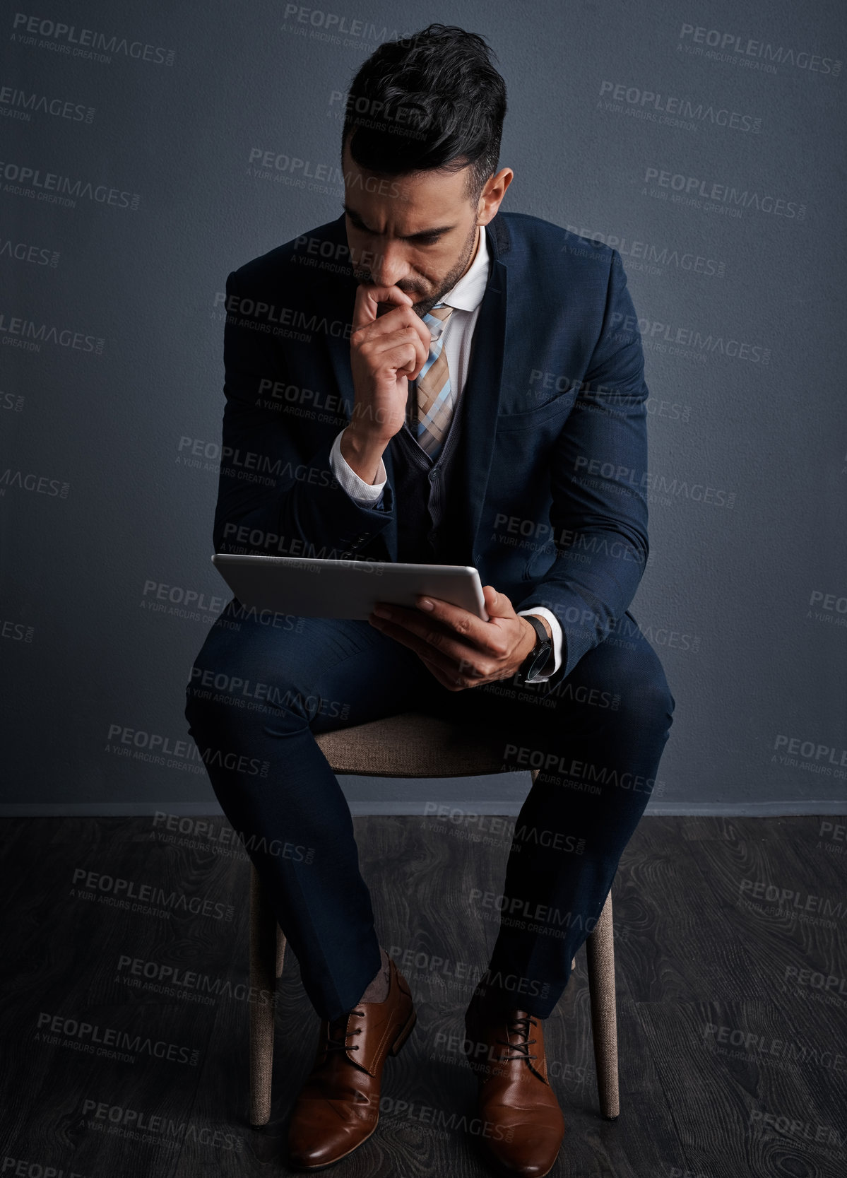 Buy stock photo Studio shot of a stylish young businessman using a digital tablet against a gray background