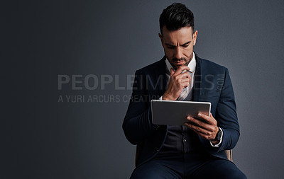 Buy stock photo Studio shot of a stylish young businessman using a digital tablet against a gray background