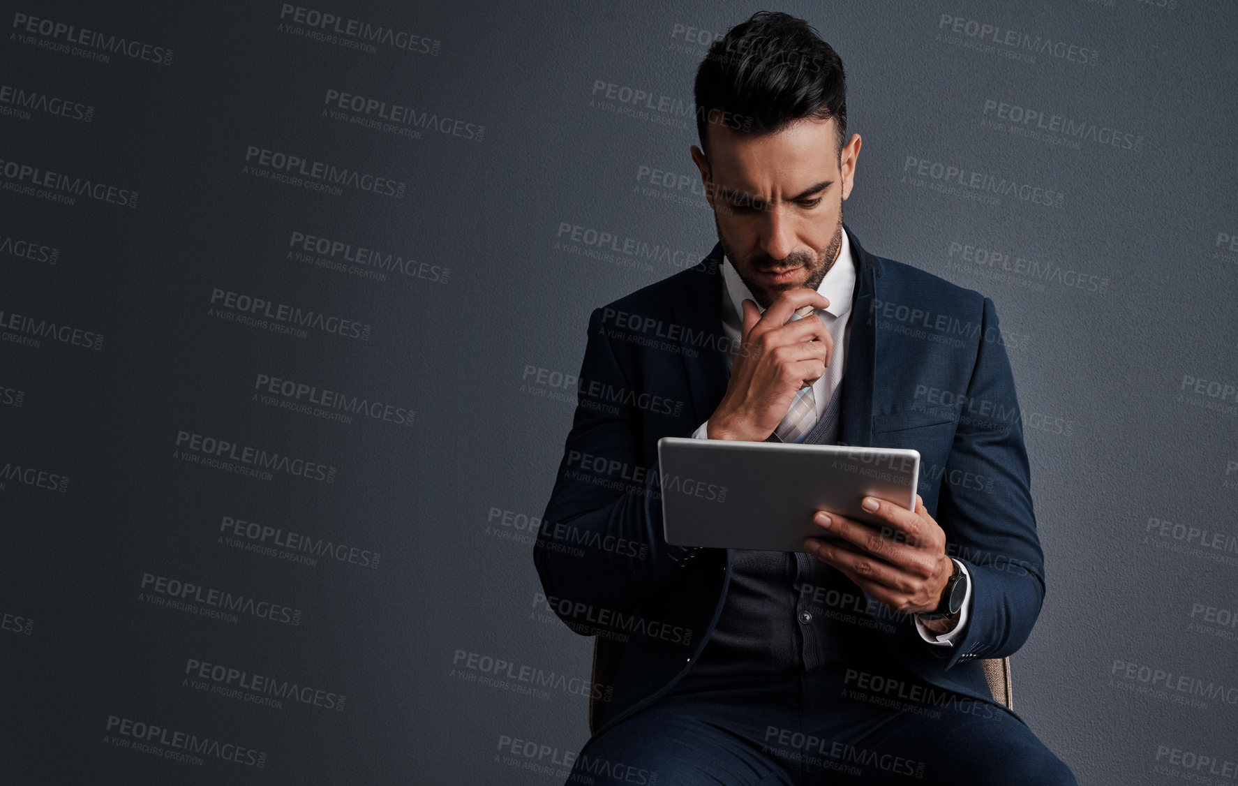 Buy stock photo Studio shot of a stylish young businessman using a digital tablet against a gray background