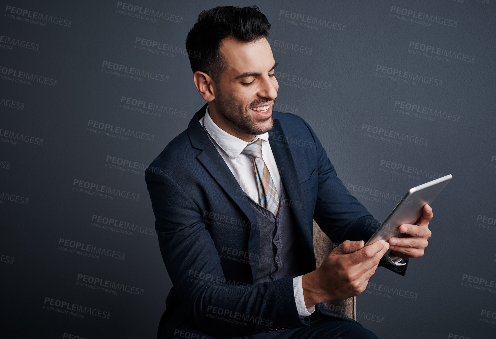 Buy stock photo Studio shot of a stylish young businessman using a digital tablet against a gray background