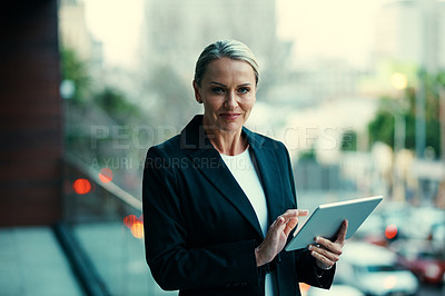 Buy stock photo Portrait of a mature businesswoman standing outside on the balcony of an office and using a digital tablet