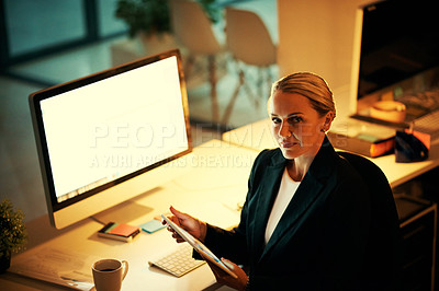 Buy stock photo Shot of a mature woman using her digital tablet while working late at the office