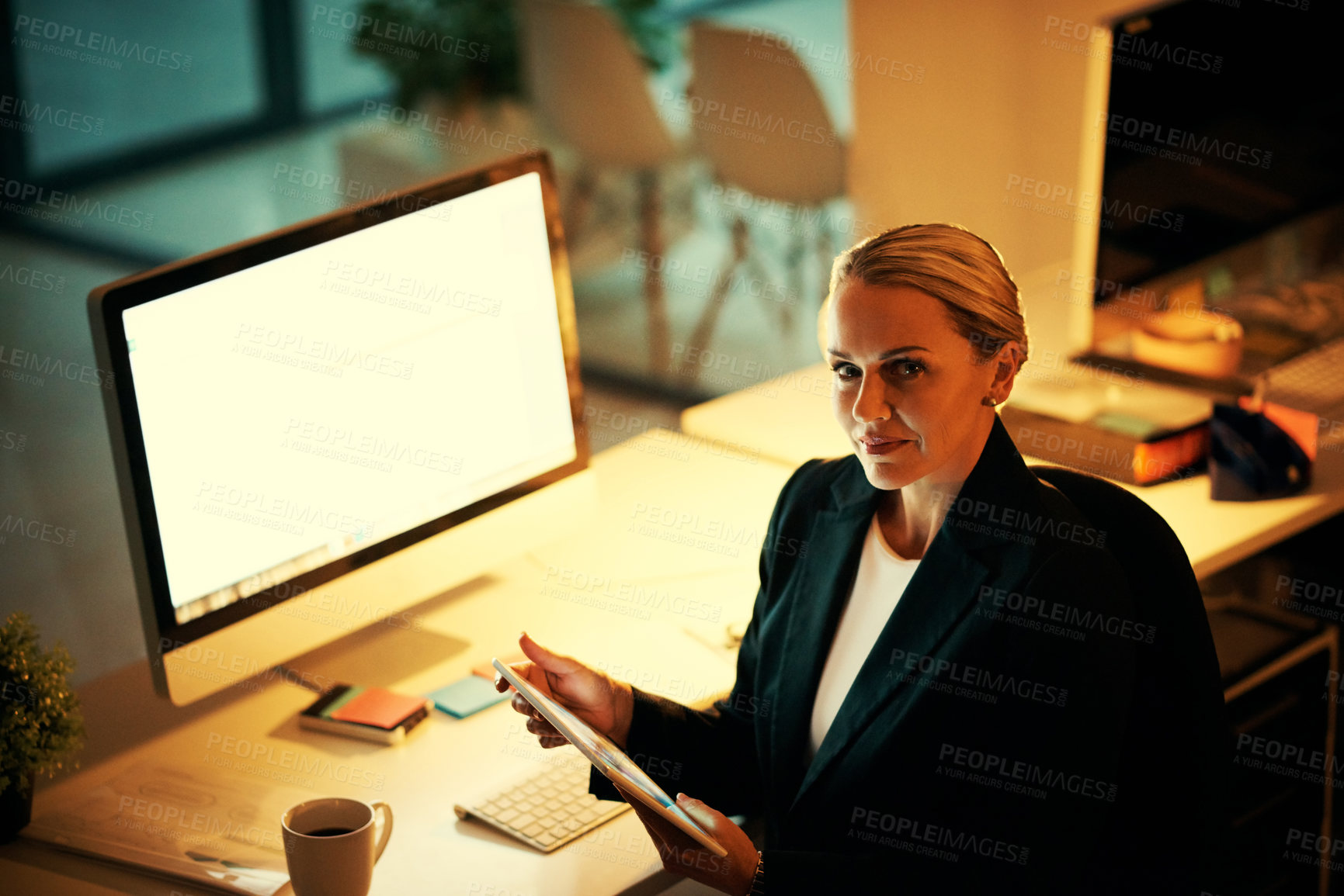 Buy stock photo Shot of a mature woman using her digital tablet while working late at the office