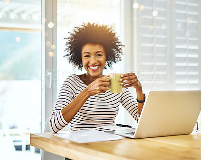 Buy stock photo Portrait of a cheerful young woman working on a laptop and drinking coffee while looking at the camera at home