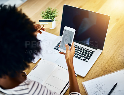 Buy stock photo Over the shoulder shot of a unrecognizable woman using her cellphone and working on her laptop at home