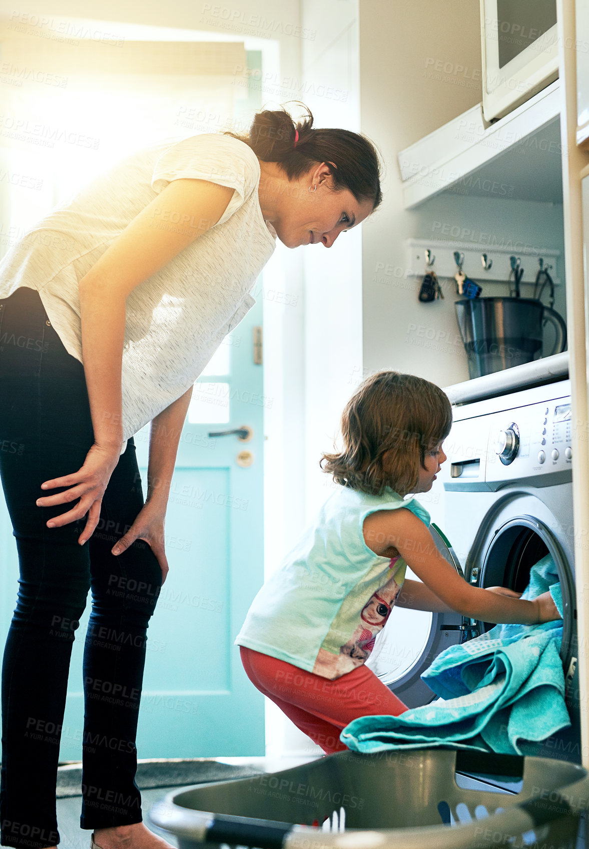 Buy stock photo Help, home and mom with kid at washing machine for chores, teaching and learning housekeeping routine. Laundry, mother and daughter cleaning clothes together with support, care and child development.