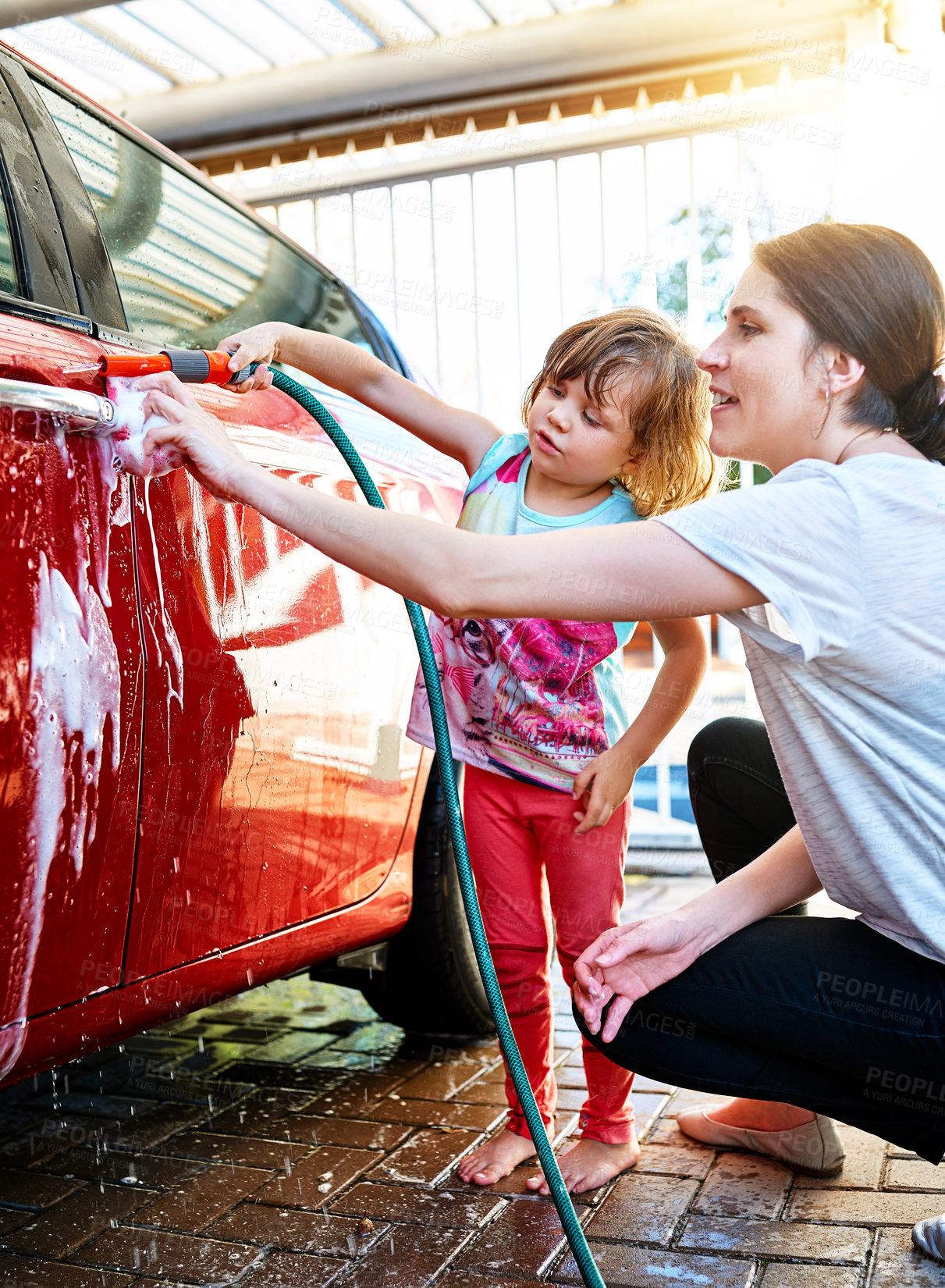 Buy stock photo Mother, child and washing car with hose pipe, water or soap for shine, chores or clean vehicle in garage. Little girl or kid helping mom with housekeeping, hygiene or bacteria, dirt or germ removal