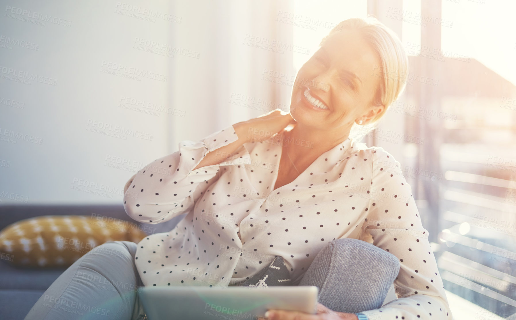 Buy stock photo Cropped shot of a mature woman using her digital tablet while relaxing at home