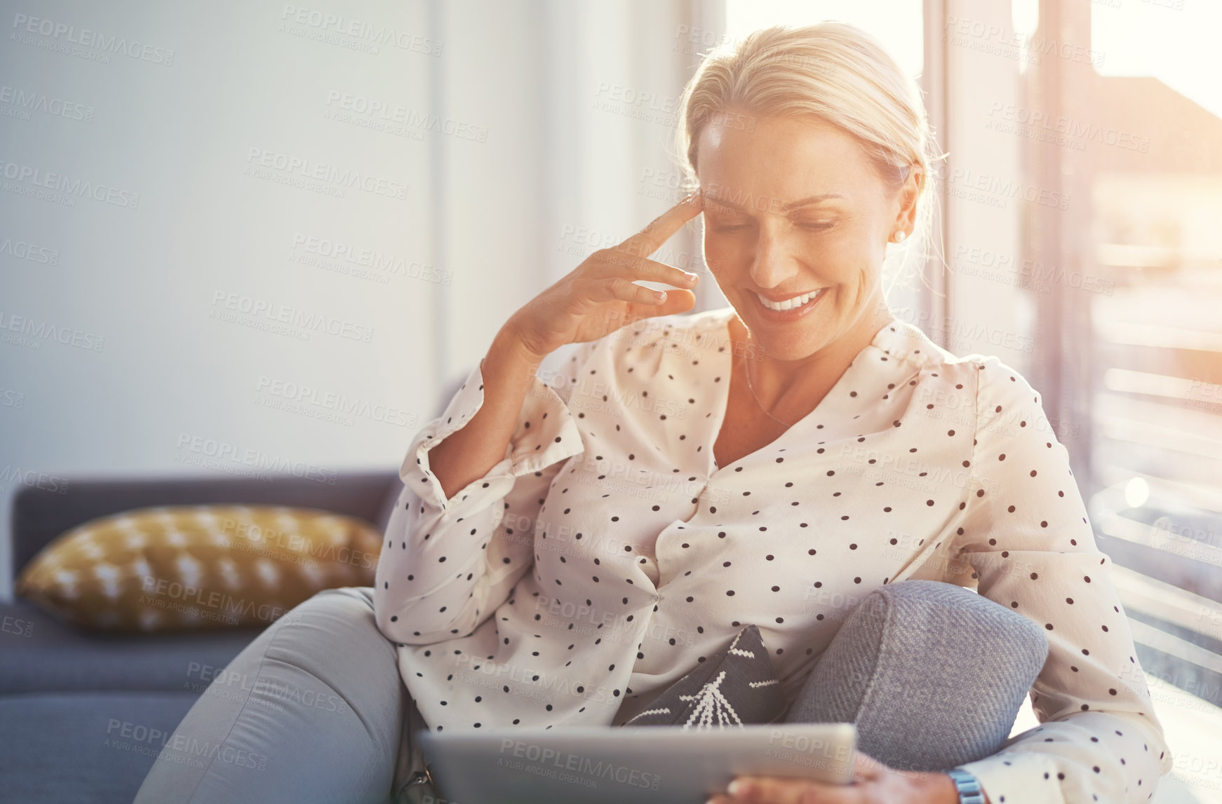 Buy stock photo Cropped shot of a mature woman using her digital tablet while relaxing at home