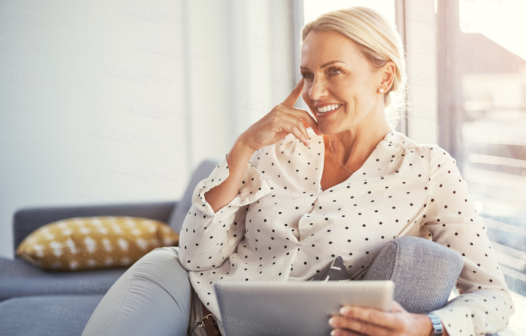 Buy stock photo Cropped shot of a mature woman using her digital tablet while relaxing at home