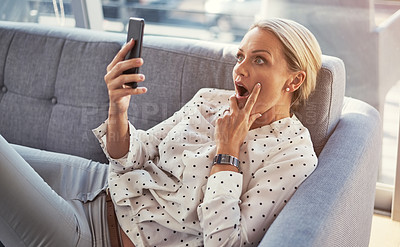 Buy stock photo Cropped shot of a mature woman using her cellphone while relaxing at home