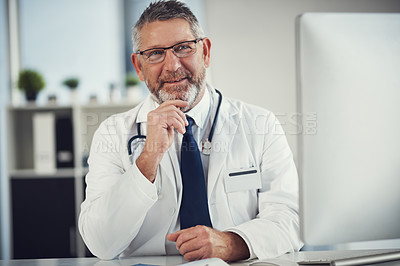 Buy stock photo Shot of a mature doctor working at a desk in his office