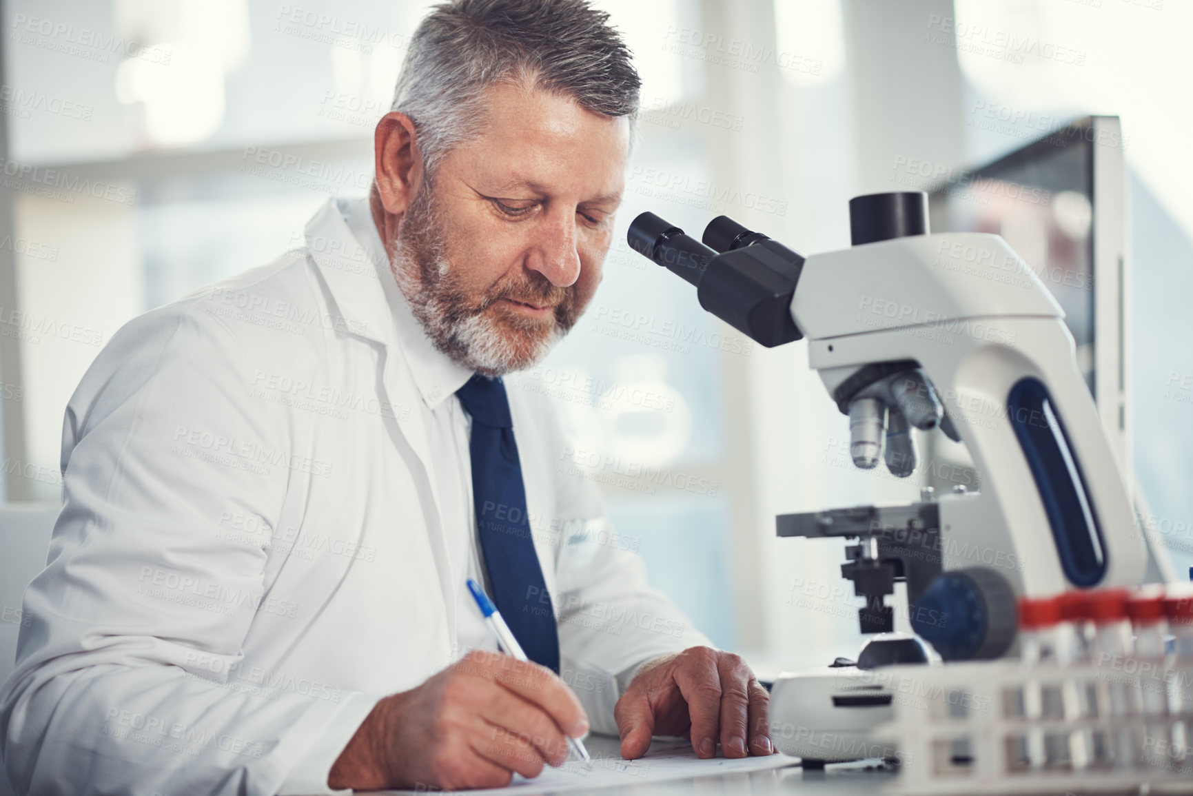 Buy stock photo Shot of a mature scientist using a microscope in a laboratory