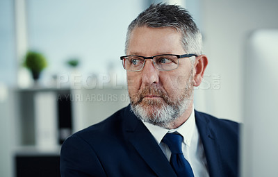 Buy stock photo Shot of a mature businessman working at his desk in a modern office