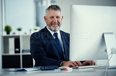 Buy stock photo Portrait of a mature businessman using a computer at his desk in a modern office