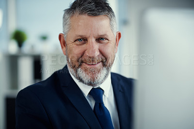 Buy stock photo Portrait of a mature businessman using a computer at his desk in a modern office