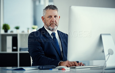 Buy stock photo Portrait of a mature businessman using a computer at his desk in a modern office