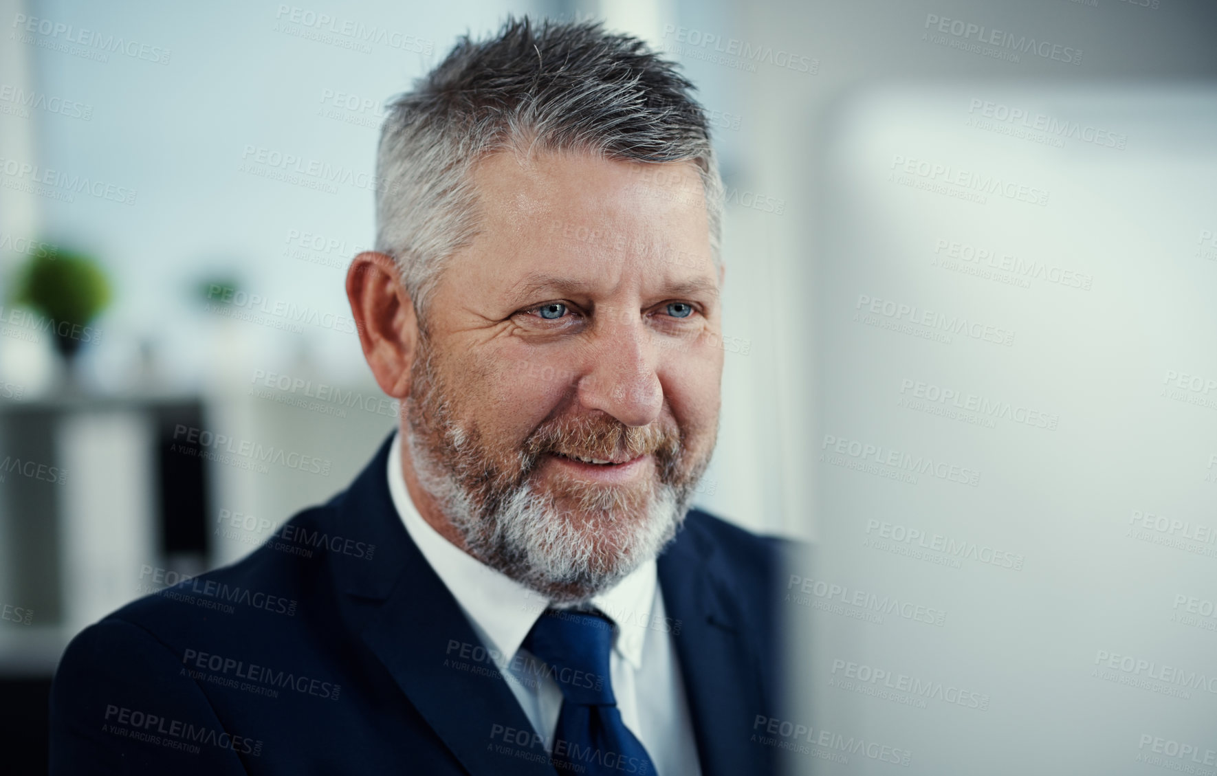 Buy stock photo Shot of a mature businessman using a computer at his desk in a modern office