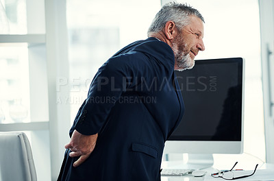 Buy stock photo Shot of a mature businessman experiencing back ache at work in a modern office