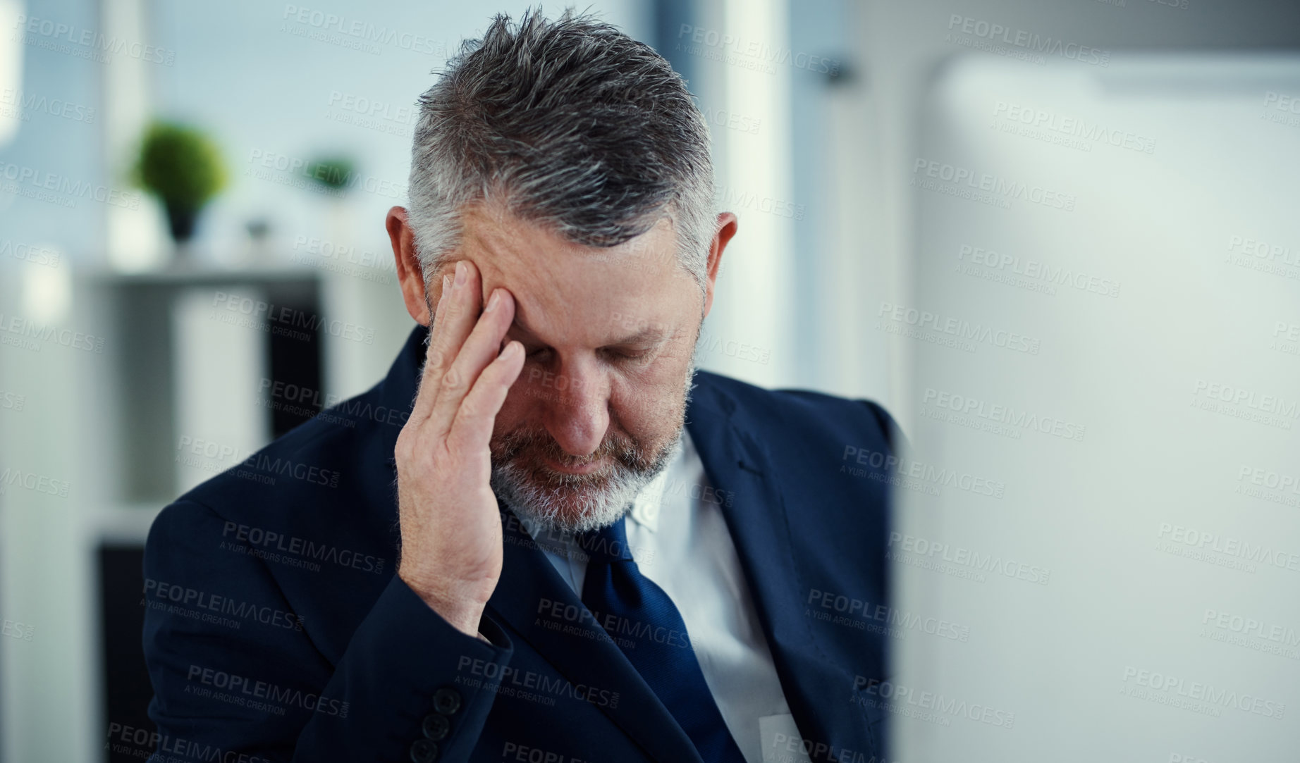 Buy stock photo Shot of a mature businessman experiencing a headache while working at his desk in a modern office