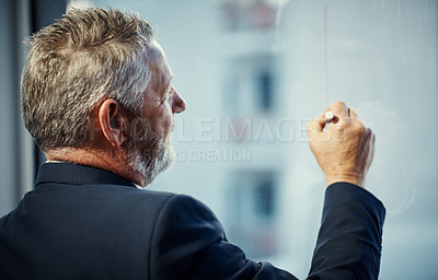 Buy stock photo Shot of a mature businessman having a brainstorming session against a glass screen in a modern office