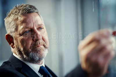 Buy stock photo Shot of a mature businessman having a brainstorming session against a glass screen in a modern office