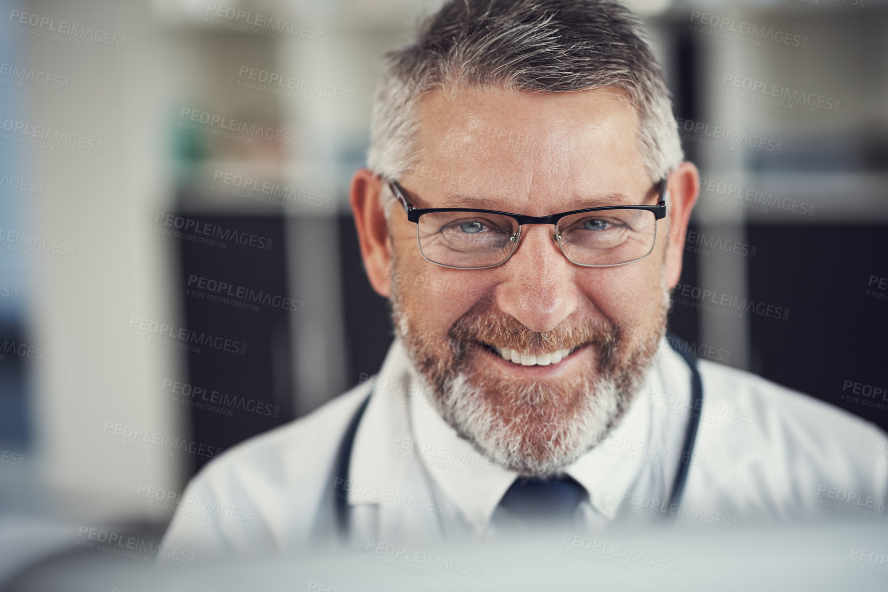 Buy stock photo Portrait of a mature doctor using a computer at a desk in his office