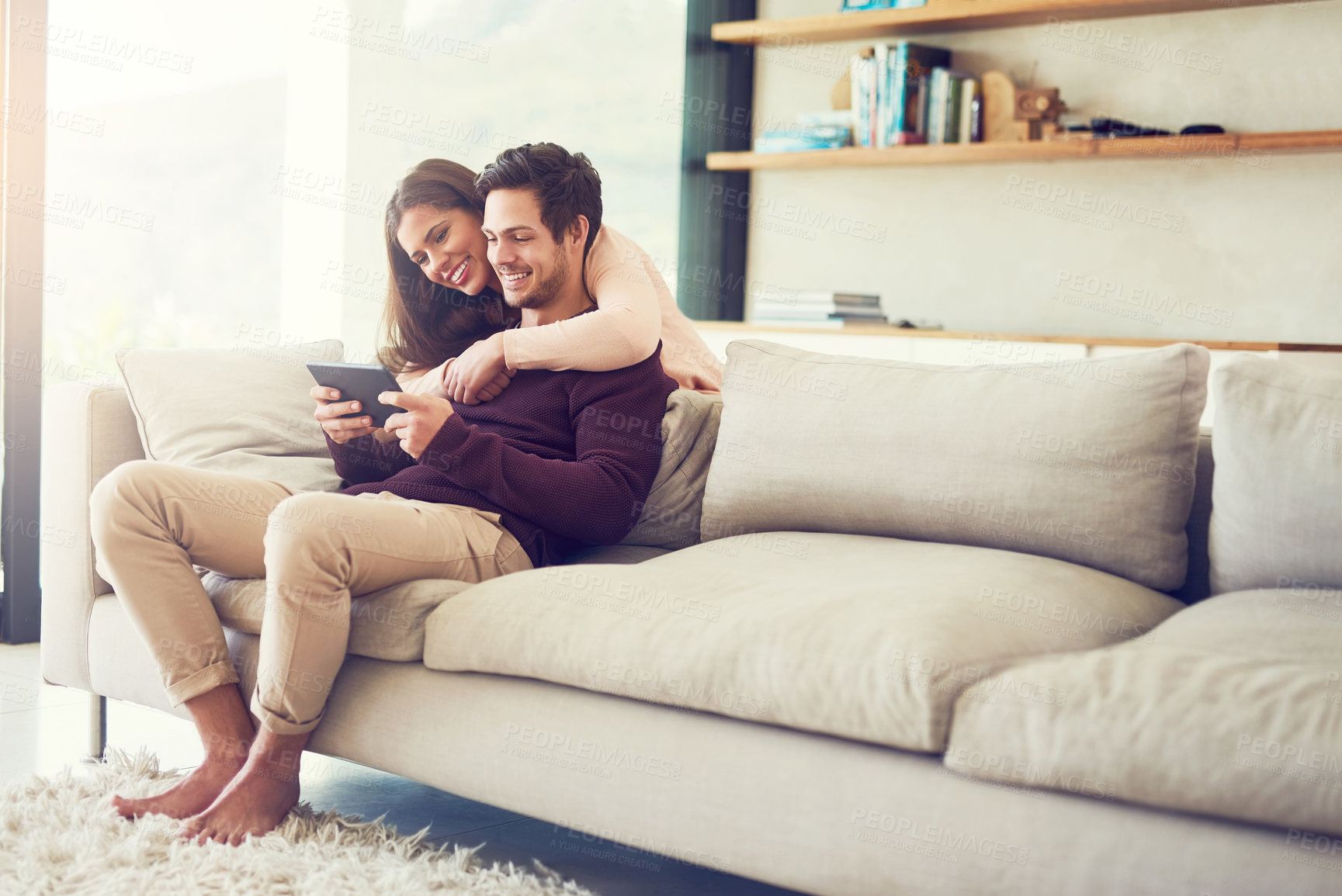 Buy stock photo Smile, couple and hug on sofa with tablet for social media, news or streaming together to relax. Digital technology, man and woman in living room for online shopping or reading blog on app in home